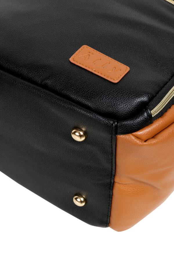 Close-up of a black and tan small diaper backpack with leather accents and metal studs.