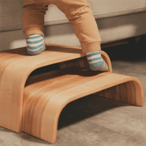 Child using adjustable wooden step stool for climbing and reaching.