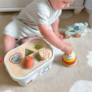 Child playing with stacking and sorting toy box on the floor.