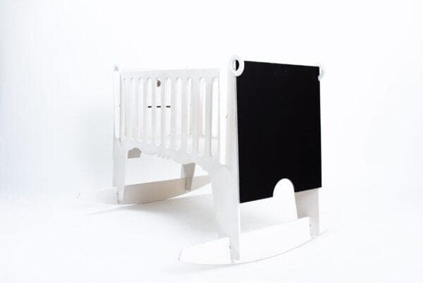 Modern white baby cradle with black chalkboard side for nursery decor.