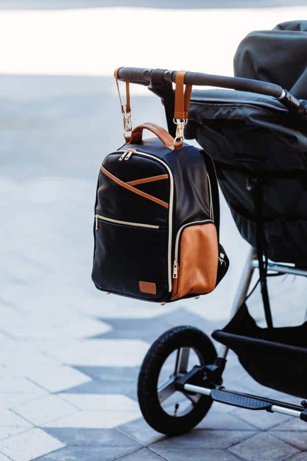 Small black and brown diaper backpack hanging from stroller handle.