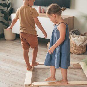 Children balancing on wooden beams in a cozy home setting.
