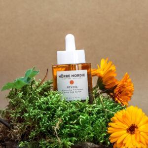 Nørre Nordic Revive Gesichtsöl-Serum in braunem Flakon mit Blüten.