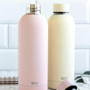 SEIK water bottles in pastel pink and cream colors on a kitchen counter.