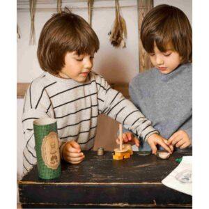 Two children playing with a wooden puzzle on a black table in a cozy room.