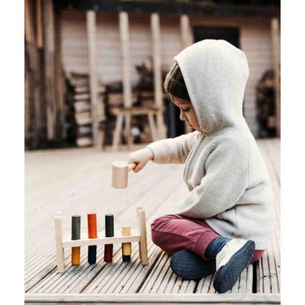 Child playing with colorful wooden pounding bench outdoors.
