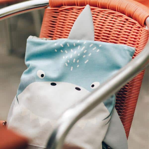 Kids backpack with shark design on a wicker chair.