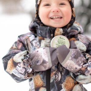 Lächelndes Kind im Winter mit Camouflage-Jacke und Mütze.