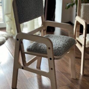 Adjustable children's chair with soft grey upholstery and wooden frame for ergonomic support.