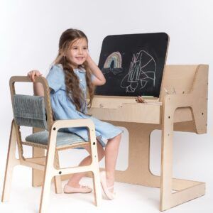 Child sitting at Montessori desk with chalkboard and drawing supplies.
