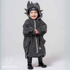 Kleines Kind in Drachen-Poncho mit Mütze und Gummistiefeln.