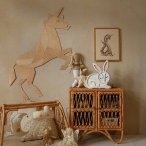 Wooden unicorn wall decoration with plush toys and framed artwork in a child's room.
