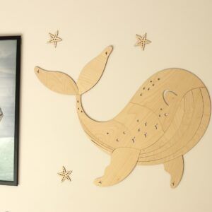 Wooden whale wall decoration with starfish on a white wall.